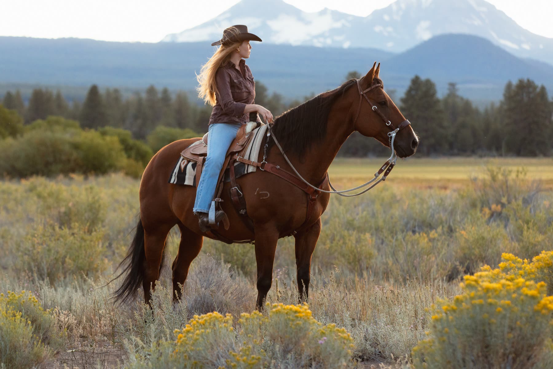 Aarica on horseback in sagebrush with mountains behind