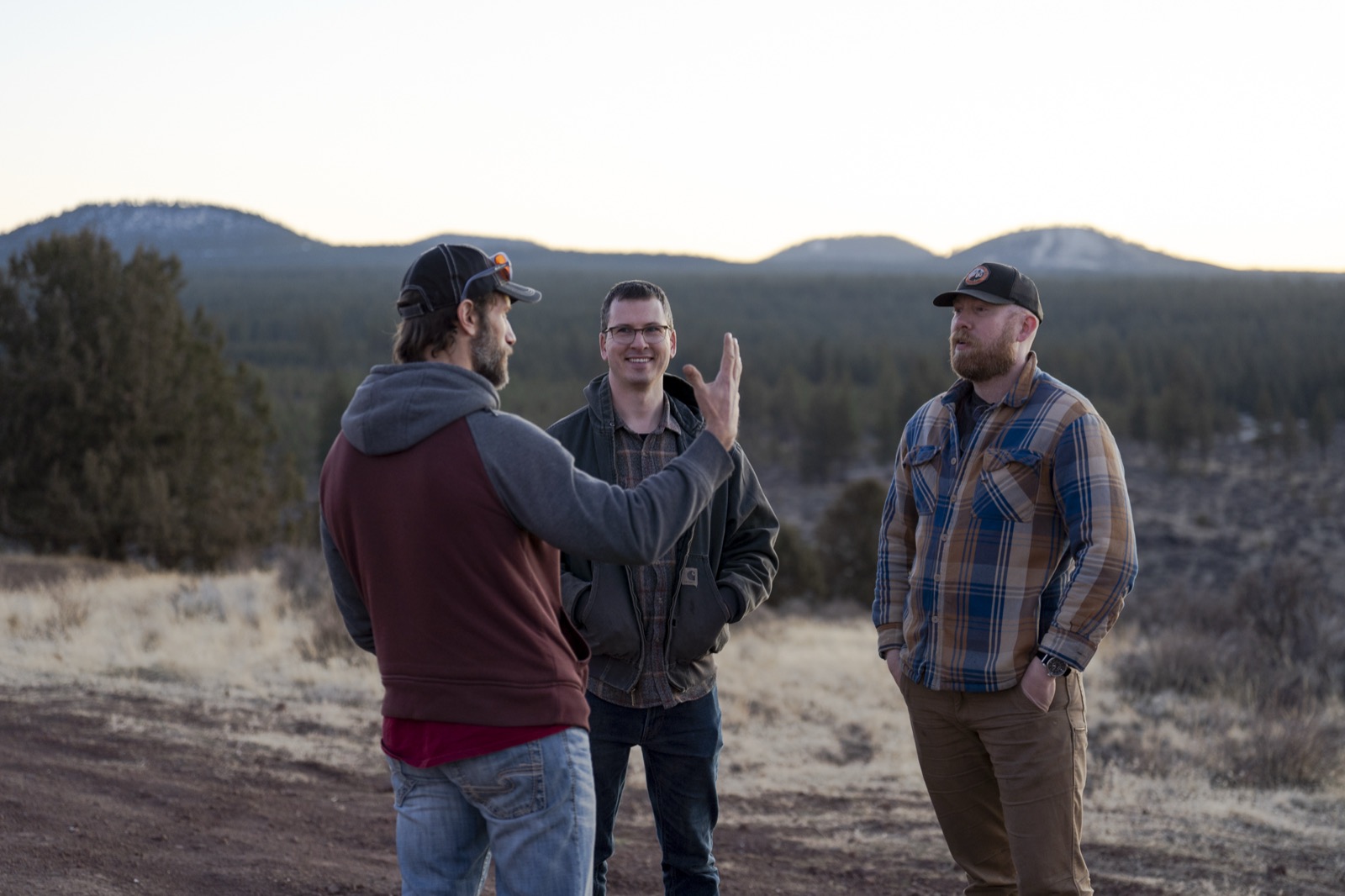 Three crew members blocking a shot on a ridge at dusk