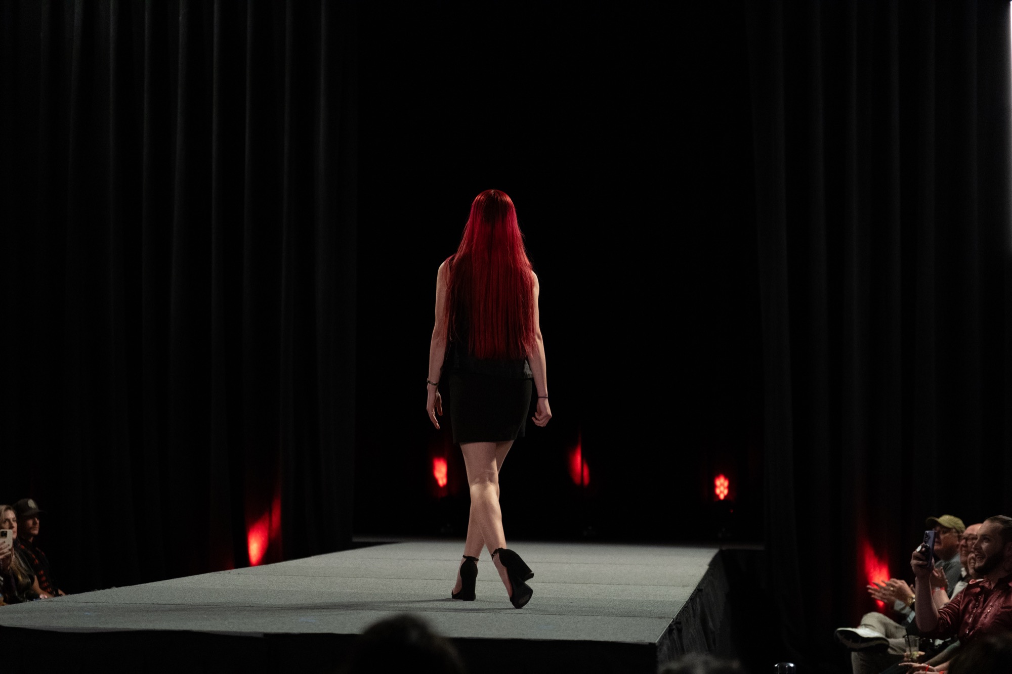 A model walking a dark runway under red accent lights