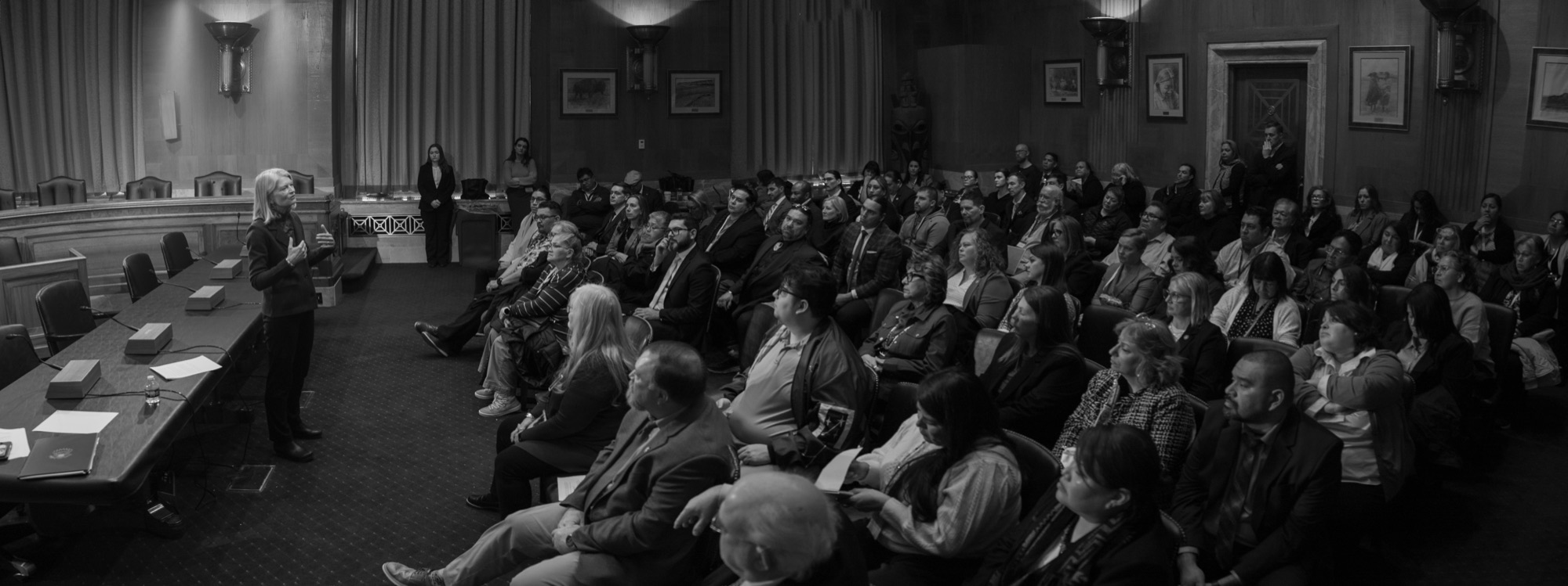 A packed Senate hearing room audience listening to testimony, in black and white