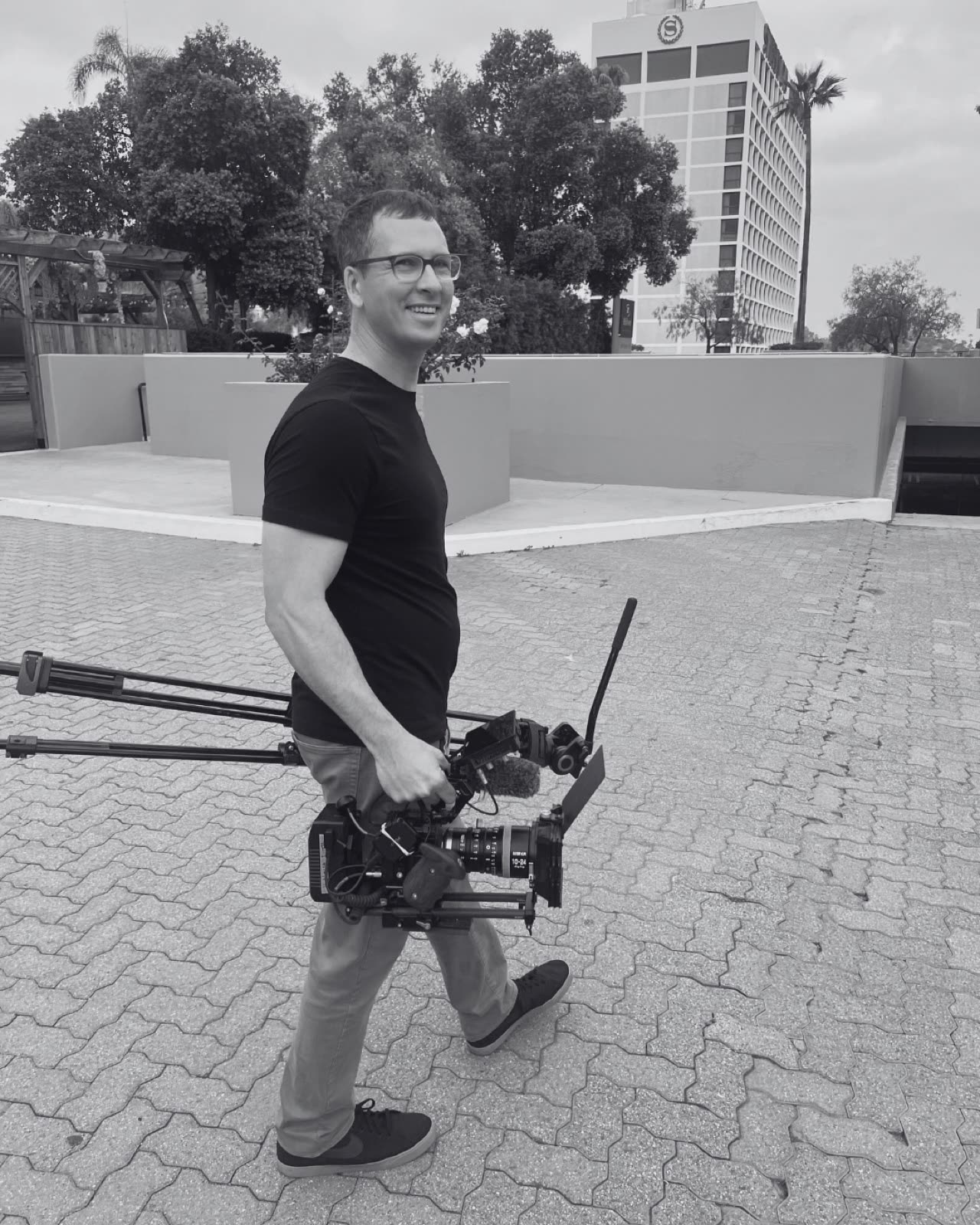 Tyler walking with a camera rig and tripod in hand